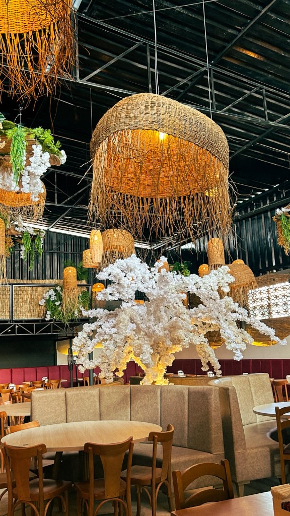 Salão principal do Costa Grill com luminárias rústicas e árvore decorativa